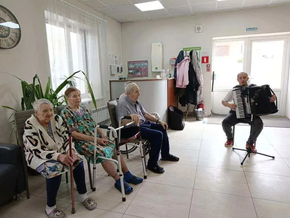 Проживающие слушают музыку в общем помещении пансионата