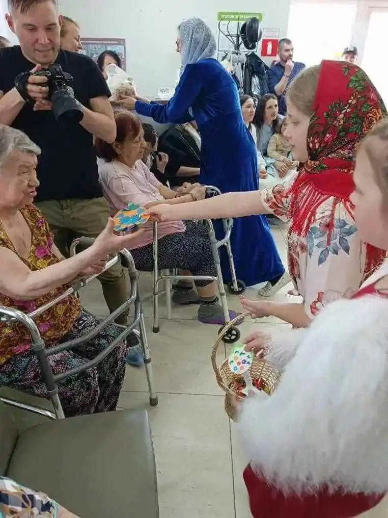 Дети в народных костюмах вручают подарки проживающим
