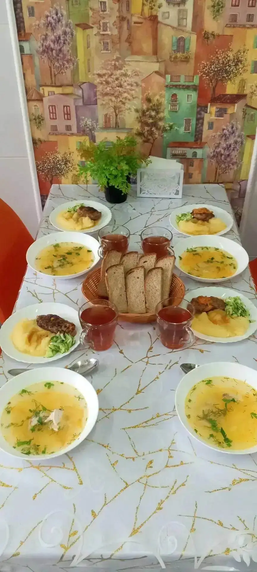 Суп и горячее блюдо с картофелем на накрытом столе