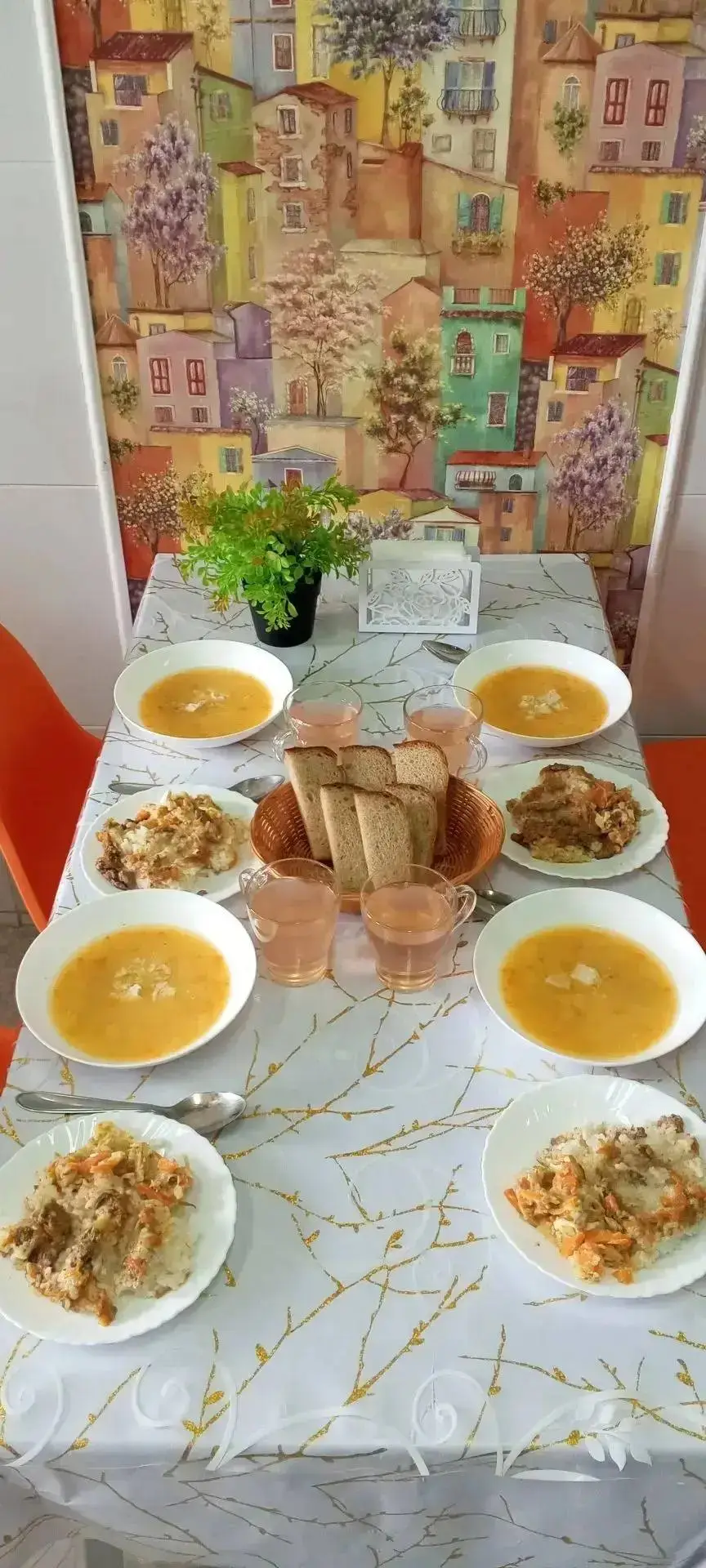 Тарелки с рисом и супом, хлеб и напитки на столе